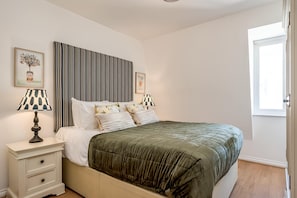 A neatly arranged bedroom with a bed, bedside tables, and a window. - Central Belfast Apartments - The Cathedral Loft (Belfast)
