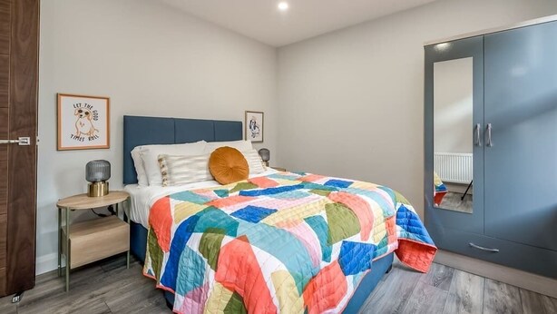 A bedroom with a bed, a wardrobe, a bedside table, and two framed pictures on the wall.