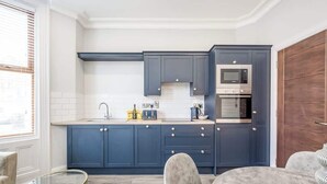 A modern kitchen with dark blue cabinets, a microwave, and a built-in oven.