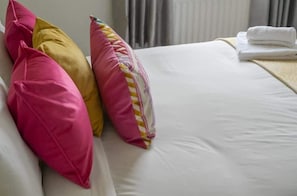 Ein Bett mit weißer Bettwäsche und bunten Kissen.