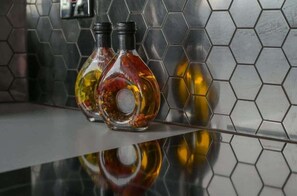 Deux bouteilles en verre, dotées d’un bouchon métallique, sont posées sur une surface réfléchissante, devant un mur recouvert de carreaux hexagonaux.