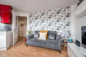 A living room with a grey sofa, a red cabinet, and a patterned wallpaper. - Central Belfast Apartments Jubilee Heights (Belfast)