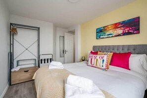 Une chambre d’hôtel avec un lit, une table de chevet, une armoire, un tableau au mur et un panneau sur le lit.