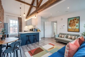 Une cuisine moderne avec un coin bar, une table à manger avec des chaises, un canapé et un tapis coloré.