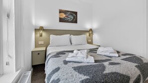 Ett hotellrum med en säng, två sänglampor, ett konstverk på väggen och ett fönster.