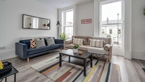 Ett modernt vardagsrum med två soffor, ett soffbord, en spegel och stora fönster med utsikt.