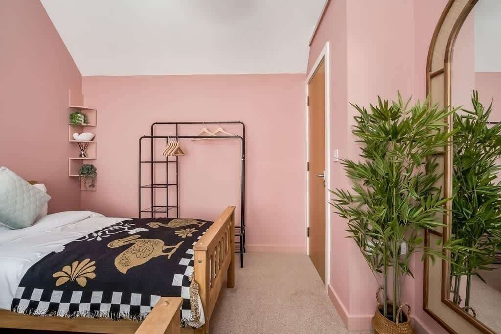 Un dormitorio con una cama doble, una escalera, un armario, un espejo y una planta en maceta.
