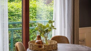 Een eettafel met een rieten mand, een vaas met groene bladeren en een houten voorwerp.