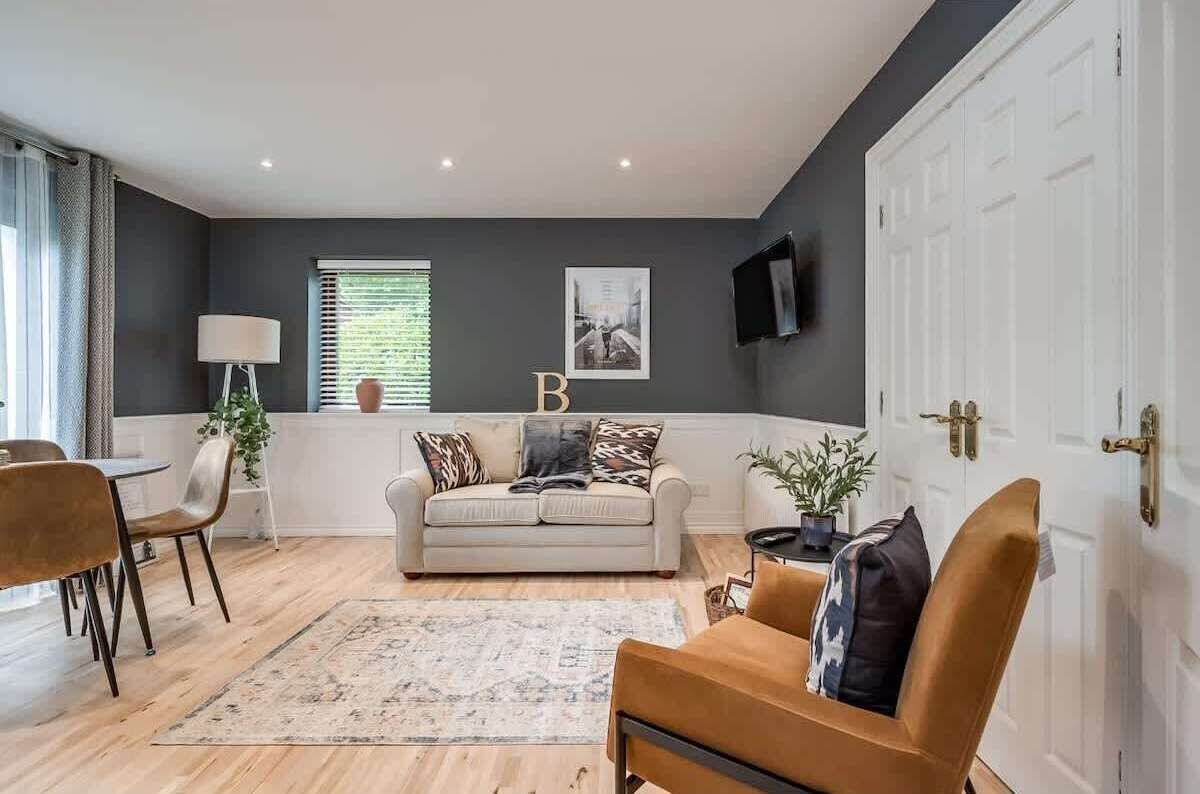 A modern living room with a sofa, chairs, a coffee table, and a rug.