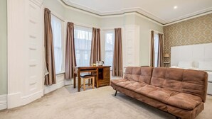 A room with a brown leather sofa, a wooden desk with a chair, and a white wardrobe. - Central Belfast Apartments Harpers (Belfast)
