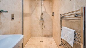 A modern bathroom with a glass-enclosed shower, a white bathtub, and a towel rack. - Central Belfast Apartments Harpers (Belfast)