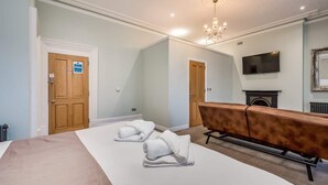 A hotel room with two beds, a fireplace, a television, and a chandelier. - Central Belfast Apartments Harpers (Belfast)