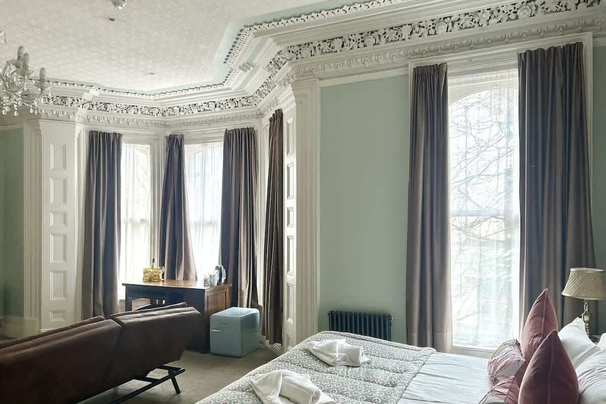A hotel room with a bed, a sofa, a desk, and a chair.