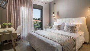 Un dormitorio moderno con una cama grande, mesitas de noche, un escritorio y vistas al exterior.