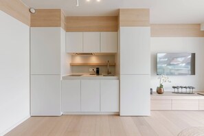 A modern kitchen with white cabinetry, a built-in oven, and a flat-screen TV mounted on the wall. - Stylish coastal apartment for 4 with sea view (Knokke-Heist)