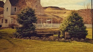 Un paysage rural avec une maison, une grange et une zone clôturée plantée d’arbres.