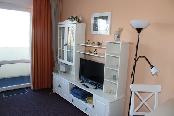 A living room with a television, white entertainment unit, and a lamp.