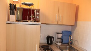 Une cuisine compacte équipée d’un four à micro-ondes, d’une machine à café et d’un évier.