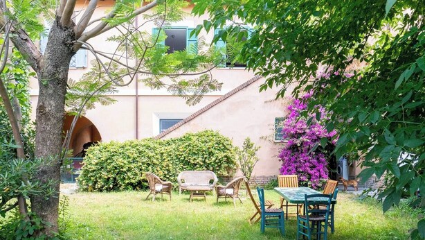 A garden with a table and chairs, a tree, and a building in the background. - A peaceful haven on Rome's doorstep (Monte dell'Ara-Valle Santa)