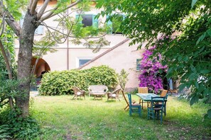 A garden with a table and chairs, a tree, and a building in the background. - A peaceful haven on Rome's doorstep (Monte dell'Ara-Valle Santa)