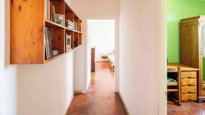 A narrow hallway with a wooden bookshelf, a wooden cabinet, and a bed in the distance. - A peaceful haven on Rome's doorstep (Monte dell'Ara-Valle Santa)