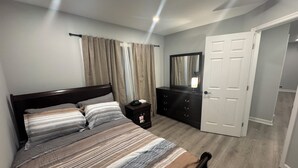 Une chambre à coucher avec un lit, une commode, un miroir et une porte.
