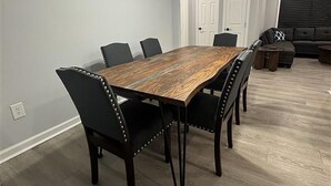 Un espace repas avec une table en bois, des chaises noires et un luminaire suspendu moderne.