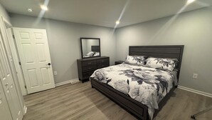 Une chambre à coucher avec un lit, une commode, une table de chevet et une porte.