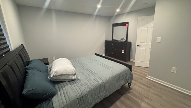 Une chambre à coucher avec un lit, une commode, un miroir et une porte.