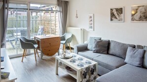 Un salon moderne comprenant un canapé, une table basse et un coin repas avec des chaises et une table.