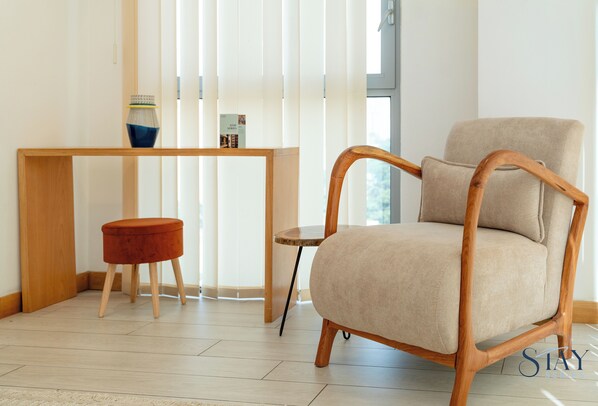 A room with a wooden chair, a small round table, and a book on a shelf.
