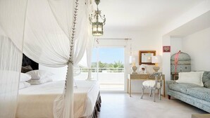 Un dormitorio con cama con dosel, un escritorio con silla, un sofá y un balcón con vistas.