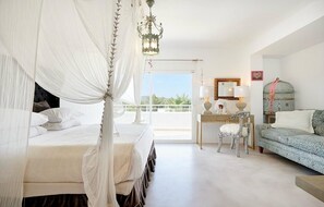 A bedroom with a canopy bed, a desk with a chair, a sofa, and a balcony with a view. - Amarantos villa: Infinity Pool & Mountain Views, 6 bedrooms, AC & WiFi (IB)