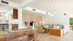 Una cocina moderna con una isla central, un comedor con sillas, un sofá y una mesa de centro.