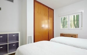 A bedroom with two beds, a wooden wardrobe, a window with a view, and a storage unit with lockers. - Amarantos villa: Infinity Pool & Mountain Views, 6 bedrooms, AC & WiFi (IB)