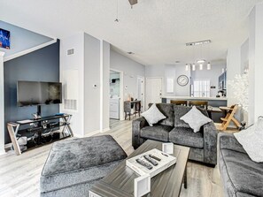Ein modernes Wohnzimmer mit einem grauen Sofa, einem Couchtisch und einem Fernseher.