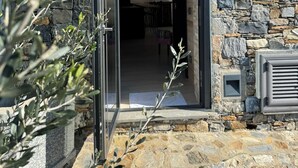 Un edificio in pietra con ingresso tramite vetrata, una mappa del mondo appesa al muro e un piccolo tavolo con sedie all'interno.