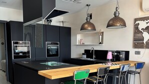 Una cucina moderna con isola centrale, sgabelli da bar e illuminazione a sospensione.