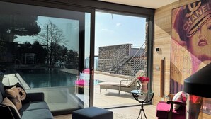 Un soggiorno moderno con un'ampia porta vetrata che dà su una zona piscina esterna.