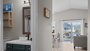 Un baño moderno con gabinetes oscuros, un espejo grande y una pintura de veleros.