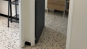 Una habitación con escritorio, silla y espejo sobre un aparador de madera.