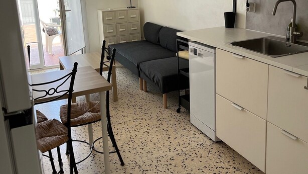 Cocina compacta con zona de comedor, sofá, microondas y fregadero.