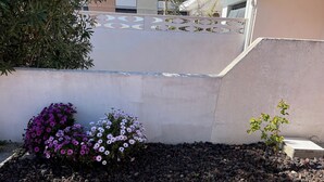 Un jardín con plantas en flor y un patio con baldosas.