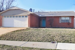 Ein eingeschossiges Haus mit Garage, Eingangstür und kleinem Vorgarten.