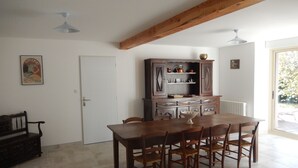 En matplats med ett träbord och stolar, ett skåp med köksutrustning, en bänk och en dörr.