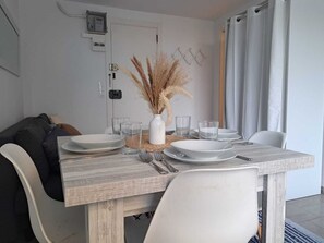 Ein Essbereich mit einem Holztisch, gedeckt für vier Personen, weißen Stühlen und einer Vase mit getrocknetem Pampasgras.