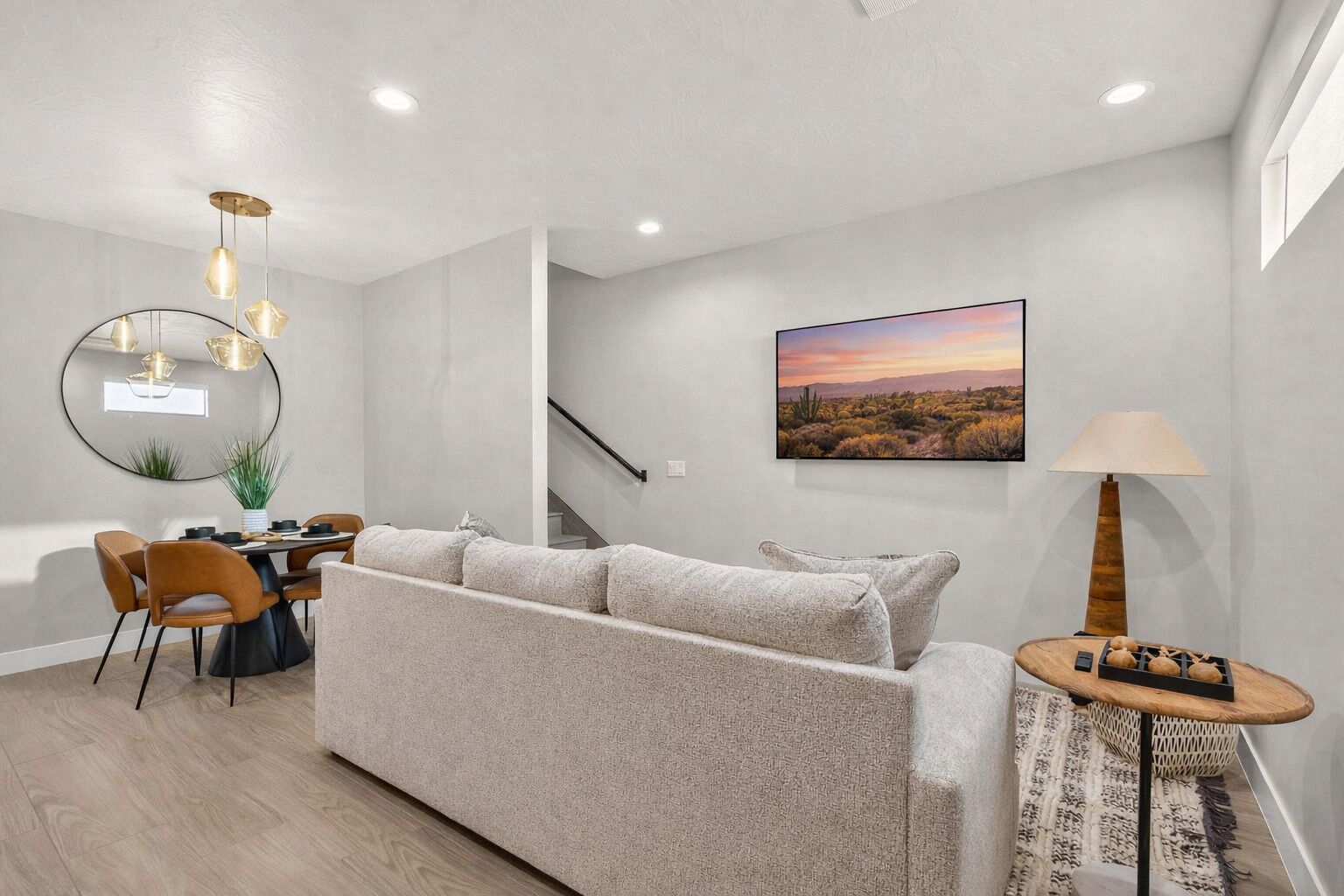 A modern living room with a sofa, dining table, chairs, and a lamp.