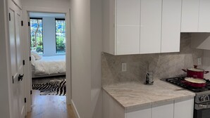 Una cocina moderna con armarios blancos, encimera de mármol y una olla roja en la estufa.