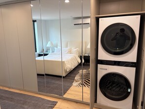 Une chambre d’hôtel équipée d’un lit, d’un miroir, d’une machine à laver et d’une armoire.