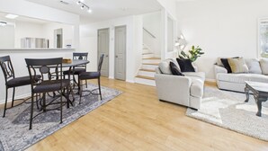 Ein modernes Wohnzimmer mit Essbereich, einer Treppe und einer Küche im Hintergrund.